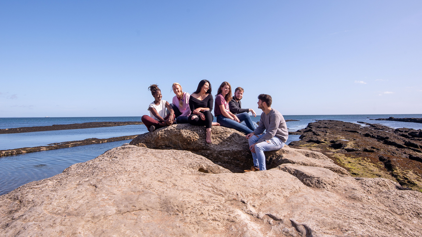 A group of students chatting by the sea.